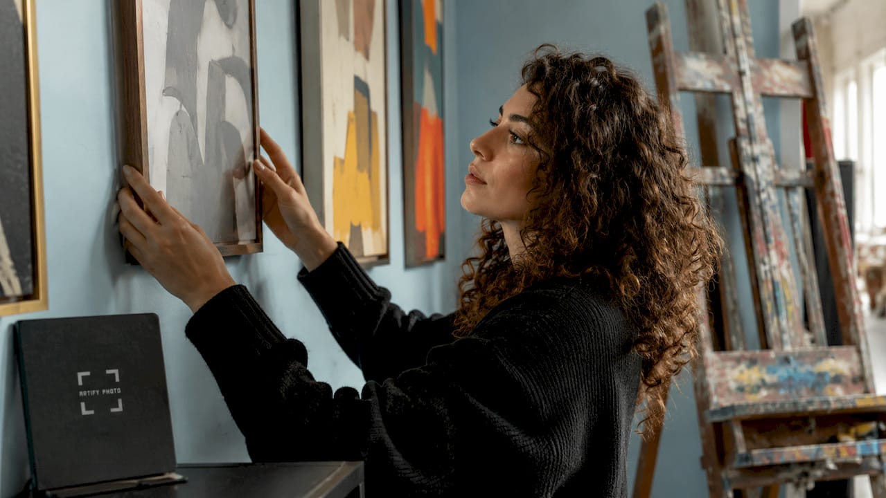 Woman arranging paintings in modern living room