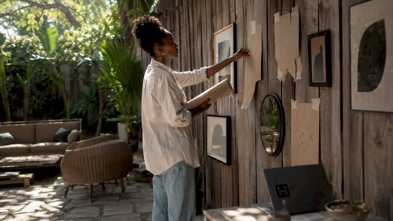 Woman arranging art templates on living room wall