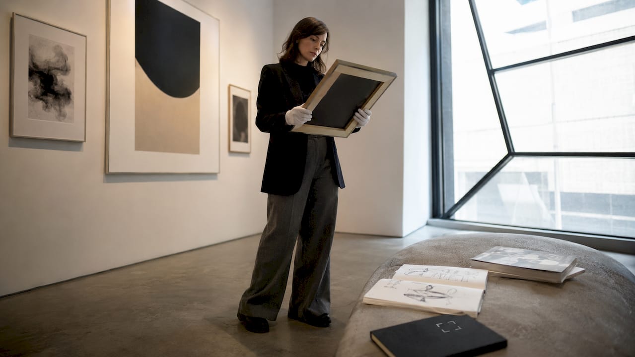 Art curator inspecting premium wall art in gallery