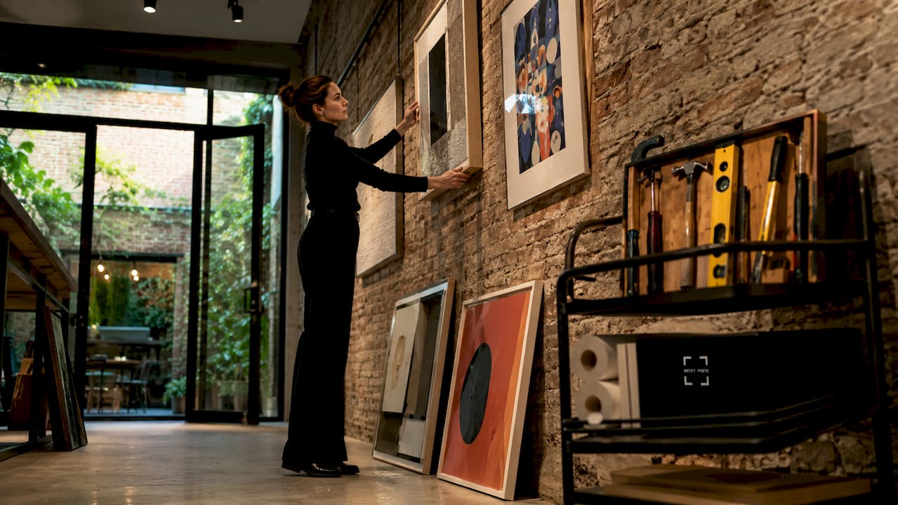 Gallery curator arranging framed wall art on gallery wall