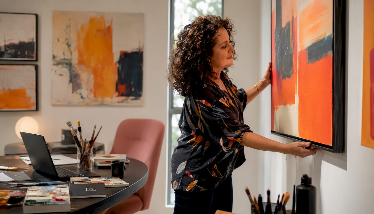 Woman hanging artwork in living room